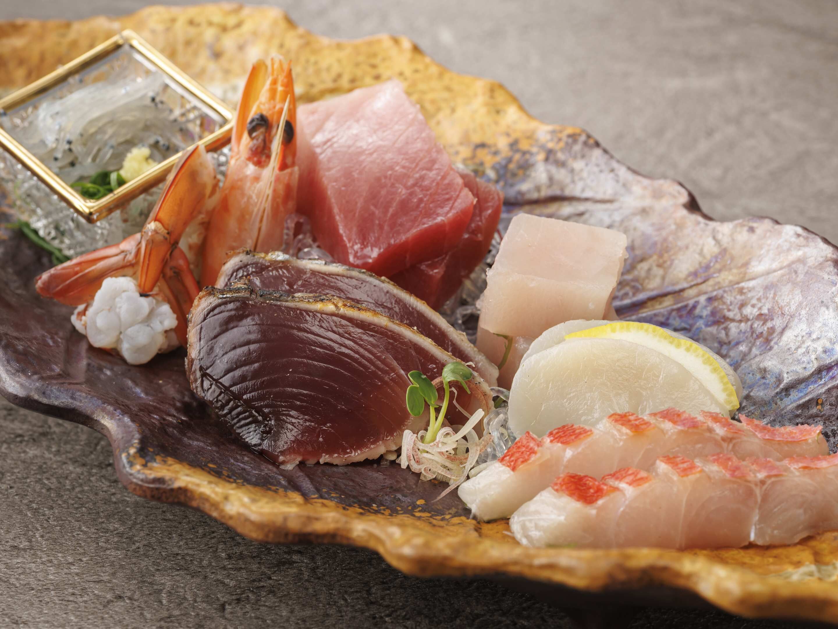 A variety of seafood including a lobster, fish, and possibly sashimi, arranged on a decorative plate.