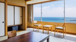 Una habitación con una mesa de madera y dos sillas, una puerta corredera y un ventanal con vistas al océano.