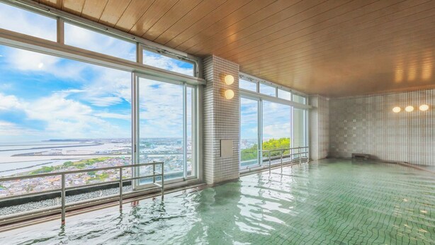 Una amplia piscina interior con ventanales que ofrecen vistas panorámicas de la ciudad.