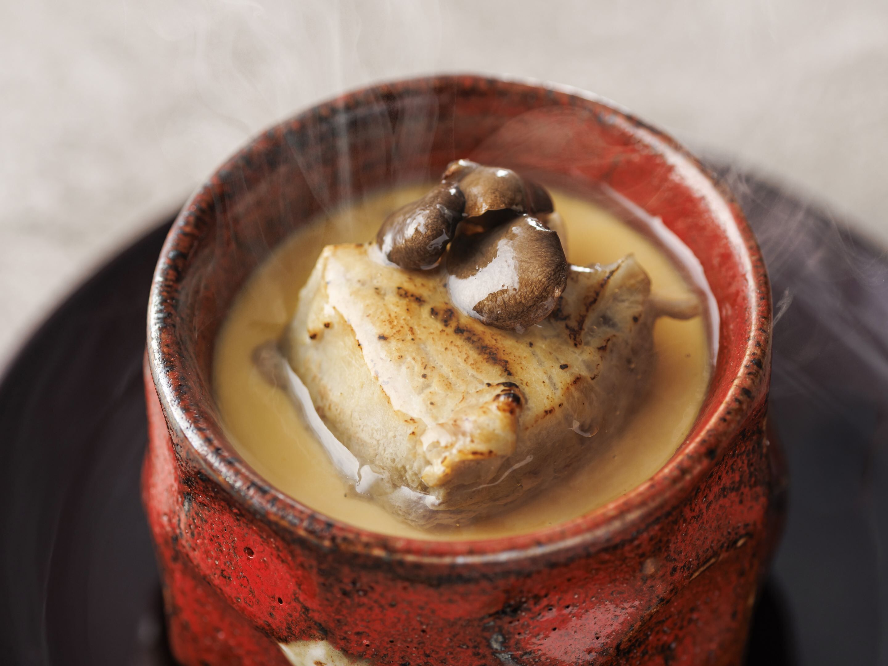 A bowl of food with a piece of meat and mushrooms.