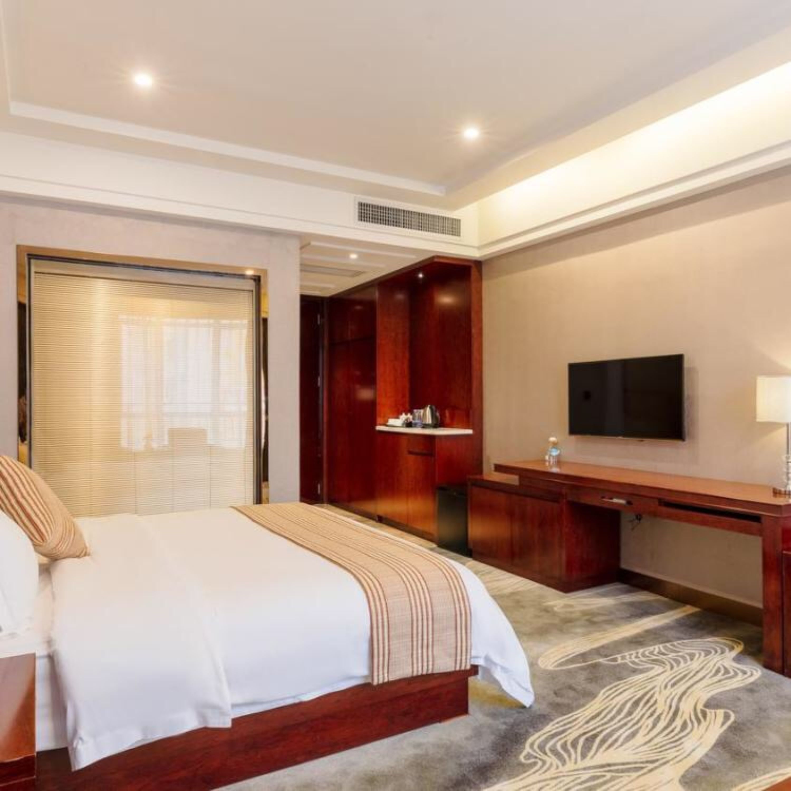 Una habitación de hotel con cama, escritorio, televisor y baño.