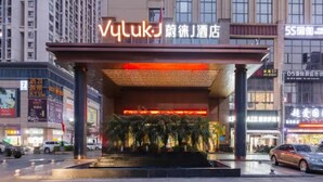 A hotel entrance with a modern design, featuring a prominent sign and a covered entrance area with steps leading up to it.