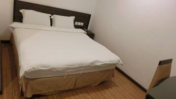A neatly made bed with white linens in a hotel room.
