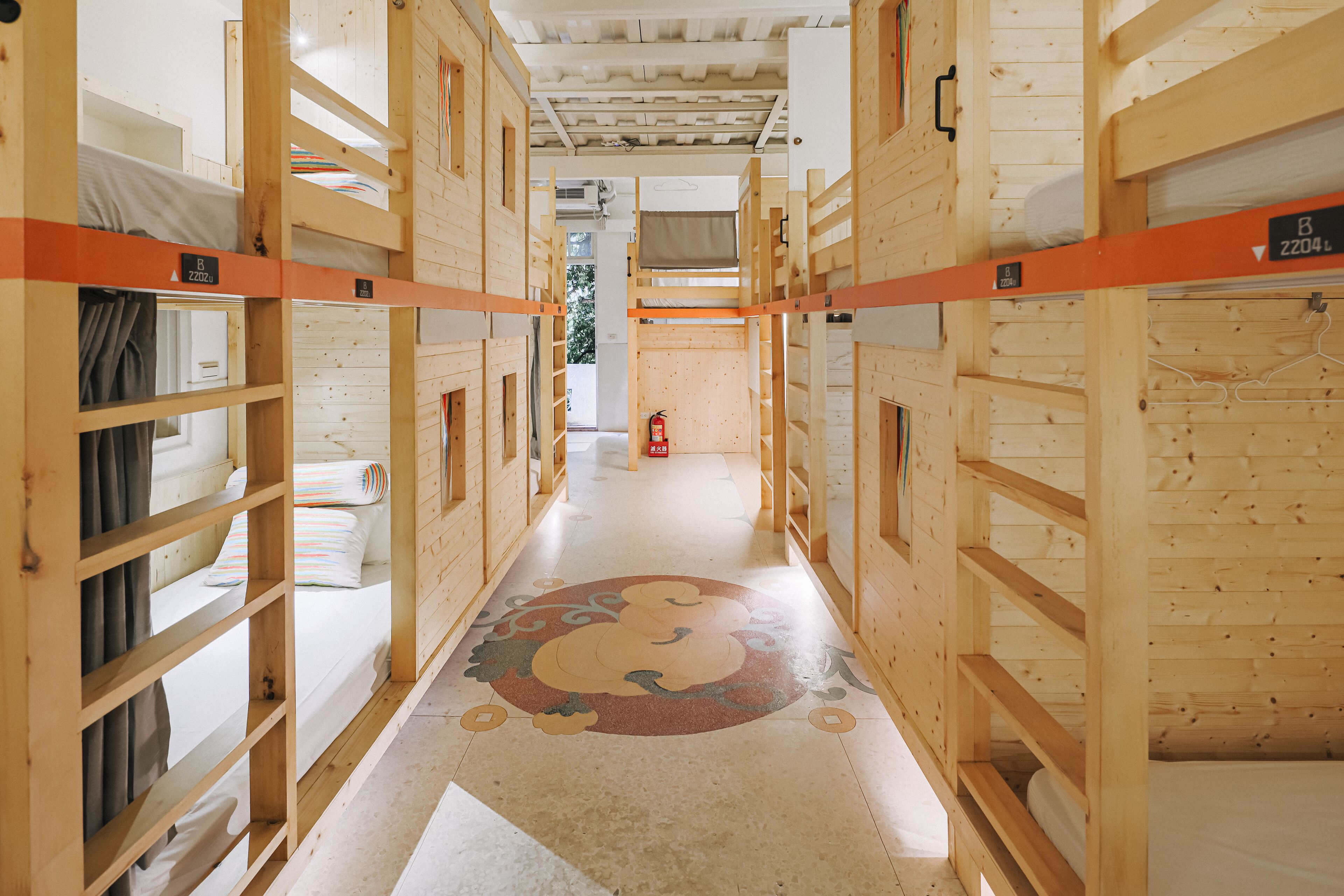 A corridor with bunk beds, wooden walls, and a patterned floor.