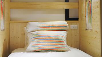 A wooden cabin room with a bunk bed, a small window, and a wall-mounted light fixture.