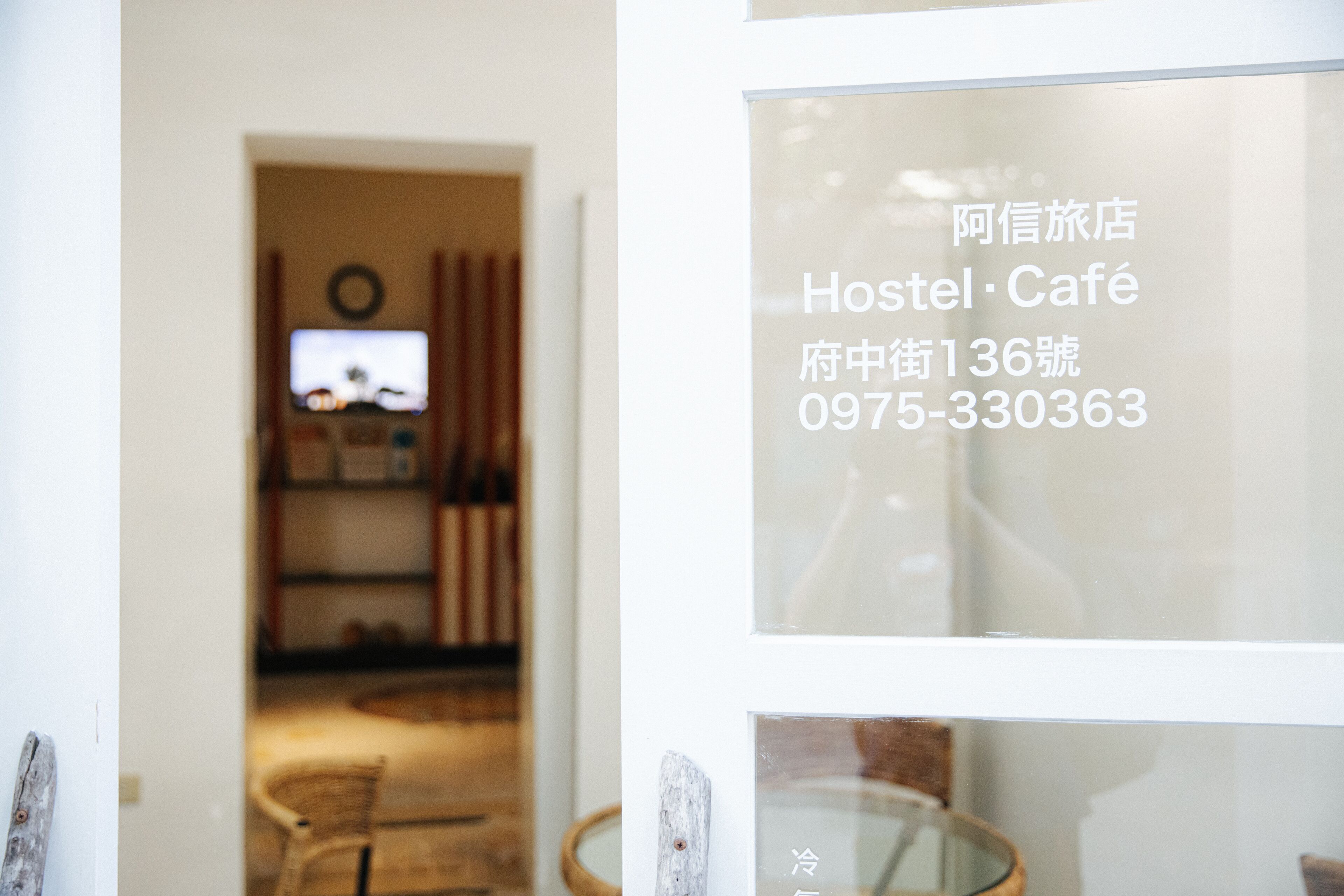 A hotel interior with a reception desk, a television, and a glass door with contact information.