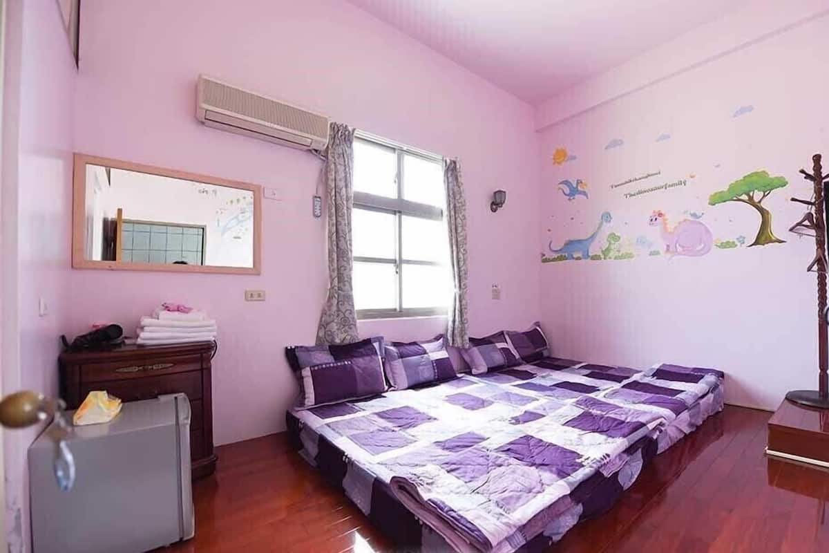 A bedroom with a bed, a dresser, a mirror, and a window with curtains.