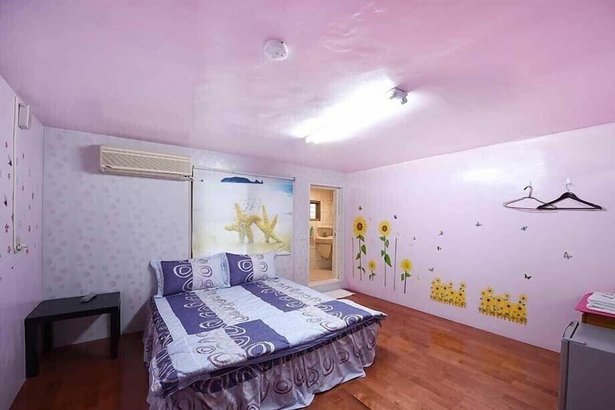 A bedroom with a bed, a small table, a wardrobe, and a wall with decorative stickers.