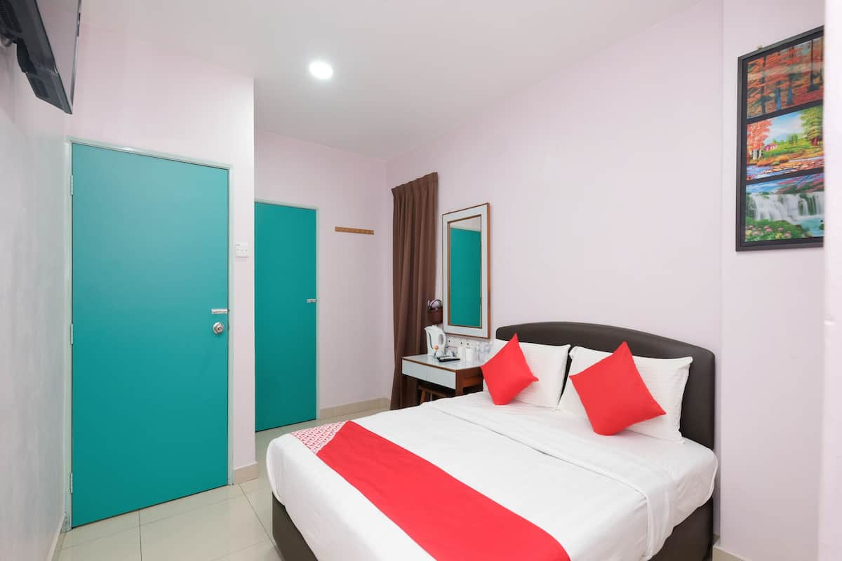 Ein Hotelzimmer mit einem Bett, einem Schreibtisch mit Spiegel, einem Fenster mit Vorhängen und einer Tür.