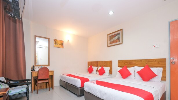 A hotel room with two beds, a desk, a chair, and a mirror. - OYO 89877 Sun Triang Hotel (Teriang)
