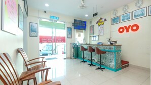 A reception area with a counter, bar stools, and wooden chairs. - OYO 89877 Sun Triang Hotel (Teriang)