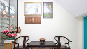 A dining area with a wooden table and chairs, a glass display cabinet, and two framed artworks on the wall. - OYO 89877 Sun Triang Hotel (Teriang)