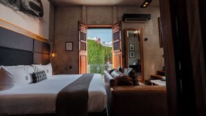 A hotel room with a large bed, a sofa, a view through an open door, and a painting on the wall. - Diez Diez Collection (Mérida)
