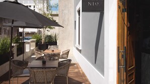 An outdoor patio with wicker furniture, a table, and a large umbrella. - Diez Diez Collection (Mérida)