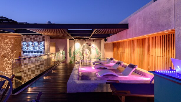 A modern spa area with a pool, lounge chairs, and a decorative wall with a neon sign. - Diez Diez Collection (Mérida)
