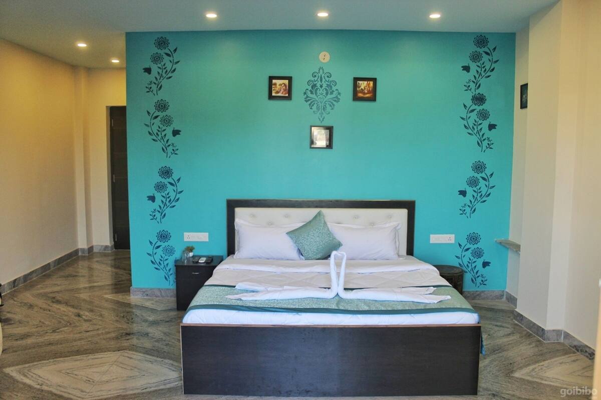 A hotel room with a large bed, a nightstand, and a wall with floral decorations.