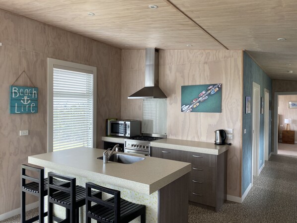 A modern kitchen with a central island, built-in appliances, and a view of the living area.