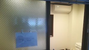 A room with a sign indicating a manager's presence, a laptop on a small table, and a green mat on the floor. - Hotel Little Bird Oku-asakusa (Tokyo)