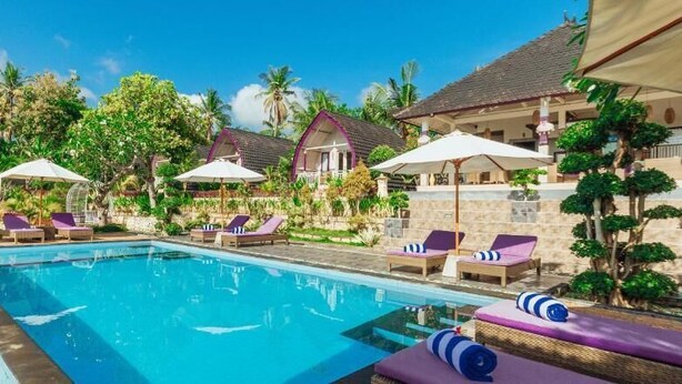 A pool area with lounge chairs and umbrellas, surrounded by buildings with a tropical architectural style. - Akusara Jungle Resort And Spa (Penida Island)