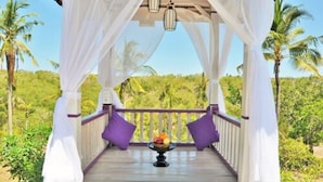 A covered outdoor seating area with a table of fruit, surrounded by white curtains and purple cushions, overlooking a tropical landscape. - Akusara Jungle Resort And Spa (Penida Island)
