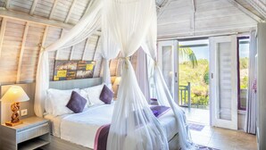 A bedroom with a canopy bed, a nightstand with a lamp, and a view of the outdoors. - Akusara Jungle Resort And Spa (Penida Island)