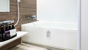 A modern bathroom with a white bathtub, a wooden vanity, and a large mirror.