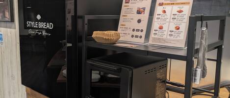 A toaster oven with a display and instructions, a bowl of bread, and a stack of plates on a wooden counter.