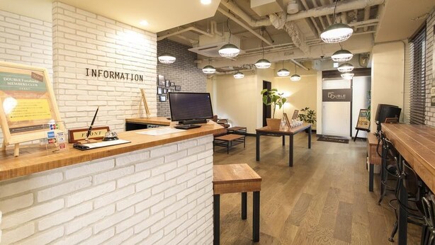 Un área de recepción con pared de ladrillo blanco, un mostrador de madera, una computadora y varias lámparas colgantes.