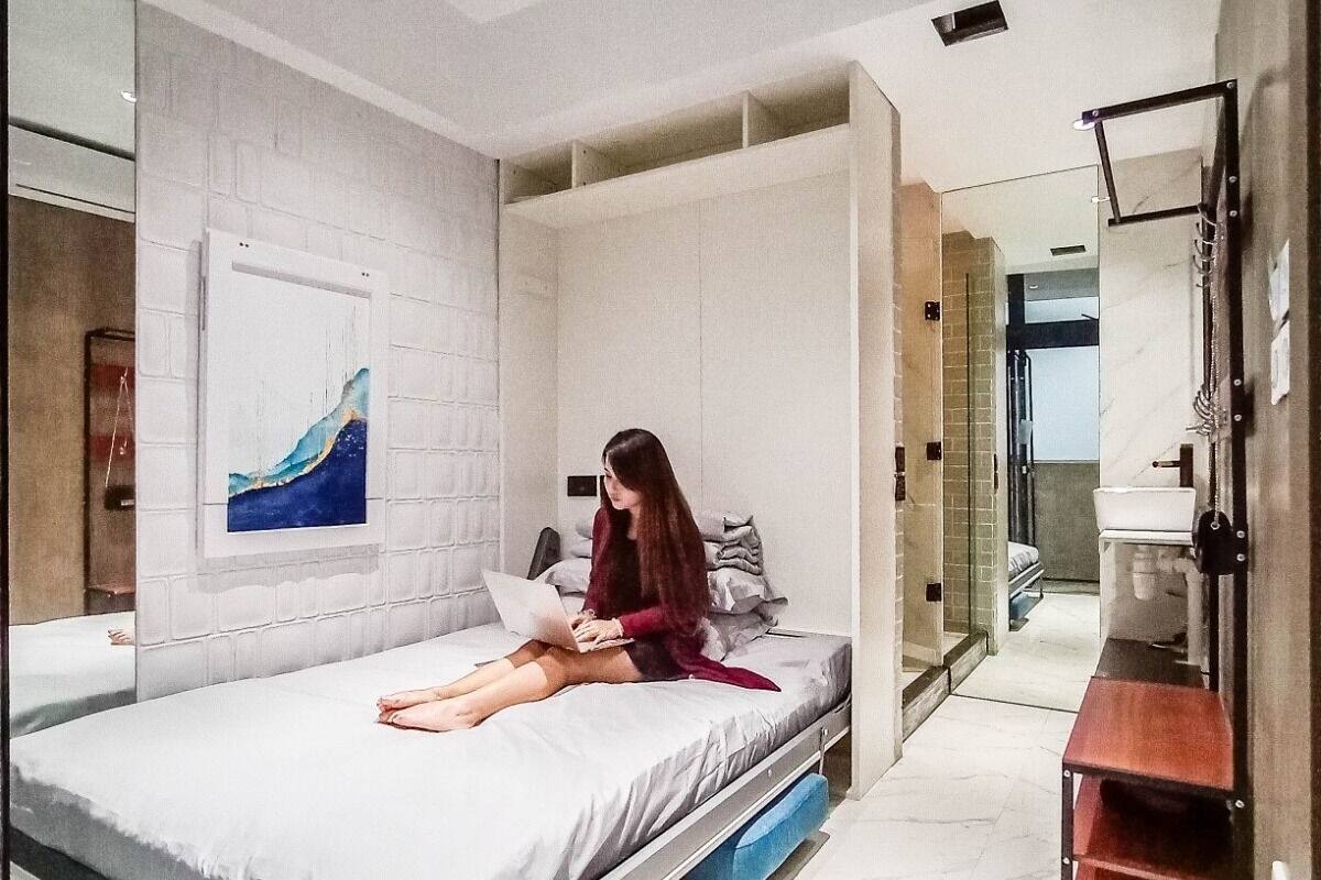 A modern bedroom with a bed, a laptop, and a large mirror.