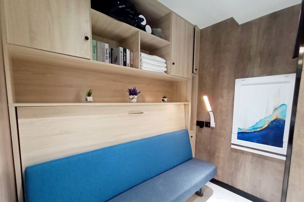 A modern room with a blue bench, wooden shelves with books and decorative items, and a wall-mounted painting.