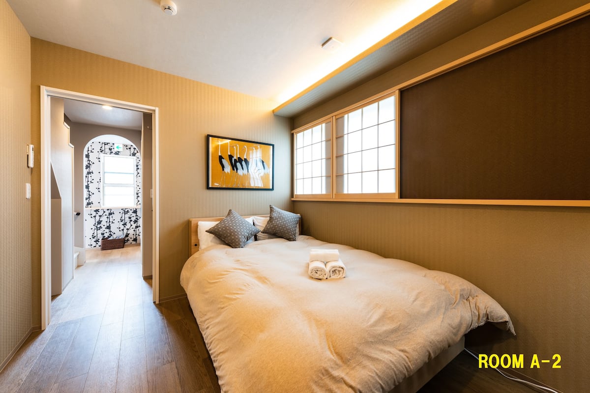 A hotel room with a large bed, a painting on the wall, and a window.