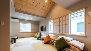 Una habitación con esteras de tatami, techo bajo y un gran ventanal con vistas.