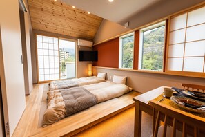Una habitación con dos camas, una mesa de comedor y un televisor.
