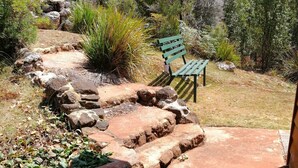 A stone staircase leading to a patio area with a green bench. - Minnow cabins, peaceful bush setting, cabin 2 (Lower Beulah)
