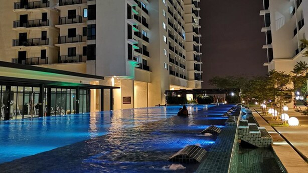 Una piscina con fuente, rodeada por un edificio de varios pisos y balcones.