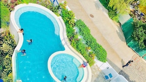 An aerial view of a swimming pool surrounded by lush greenery and a few lounge chairs. - La Bella Tagaytay Residences (Tagaytay)