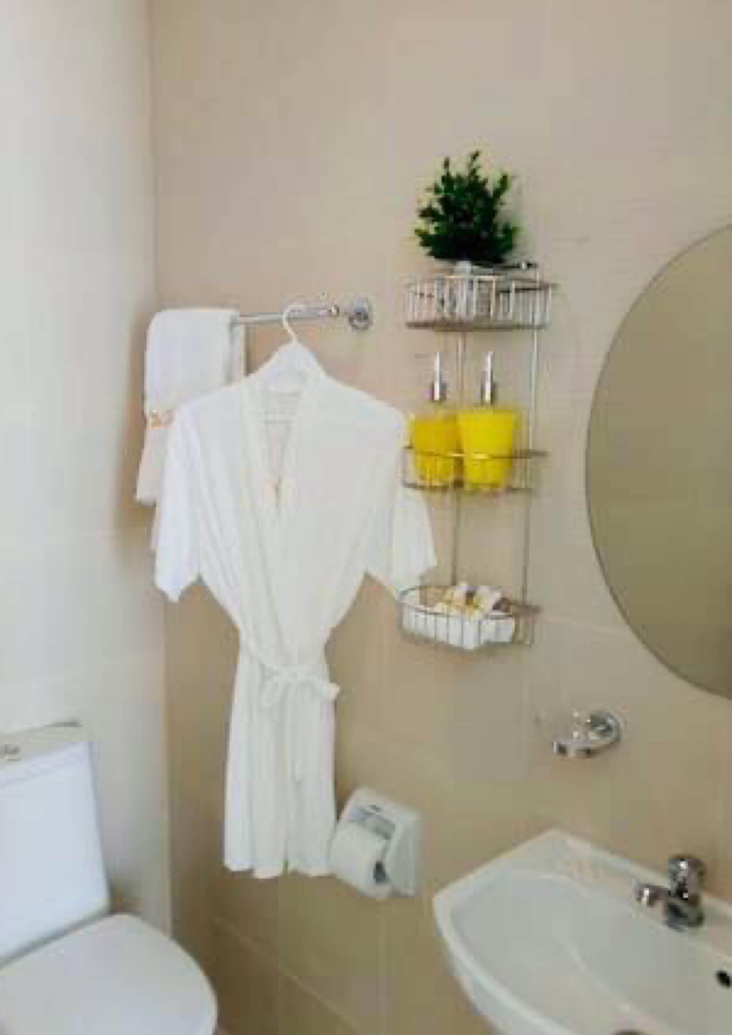 Ein Badezimmer mit Toilette, Waschbecken und einem Handtuchhalter mit Bademantel.