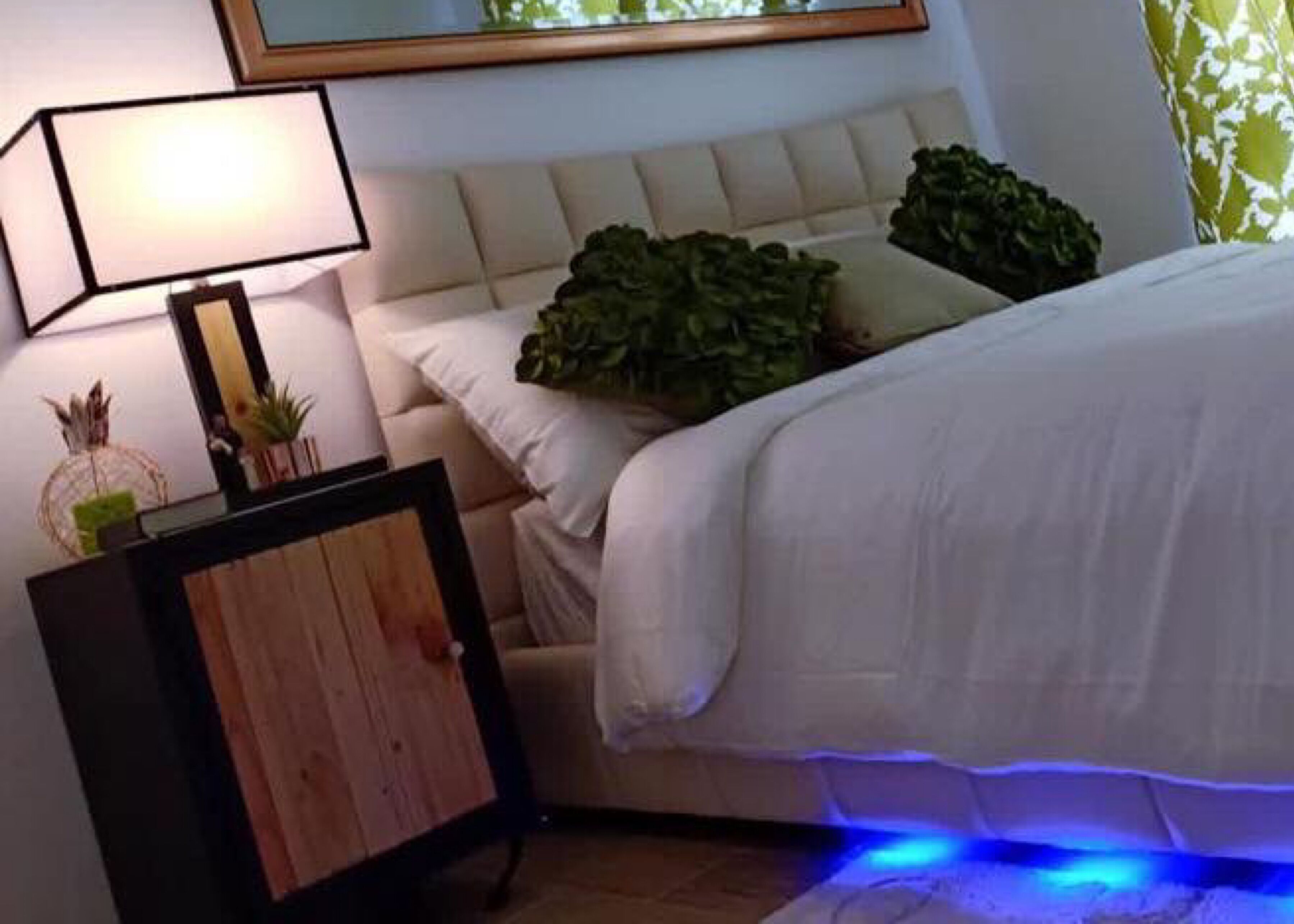 A bedroom with a bed, a nightstand, a lamp, and a mirror.