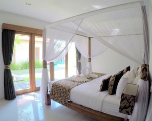 Relax in a spacious bedroom with a large bed under a canopy, surrounded by a modern design and plenty of natural light.