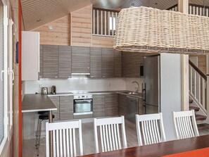 Una cucina moderna con elettrodomestici in acciaio inossidabile, un'isola centrale e una lampada a sospensione in vimini.