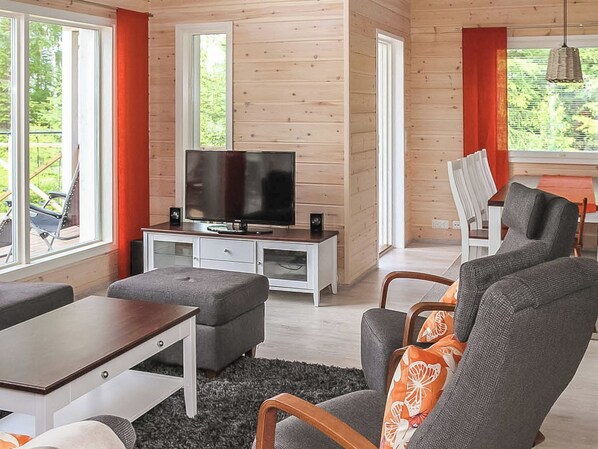 Een moderne woonkamer met een televisie, bank en eethoek.