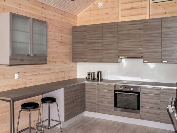 A modern kitchen with wooden paneling, stainless steel appliances, and a bar area.