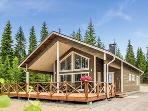 Una baita con terrazza in legno, ampie finestre e portico coperto.
