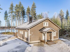 Een chalet met een schuin dak, een schoorsteen en een klein terras met treden naar de ingang.
