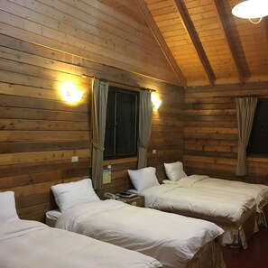 Une cabane avec deux lits, des murs en bois et un luminaire au plafond.