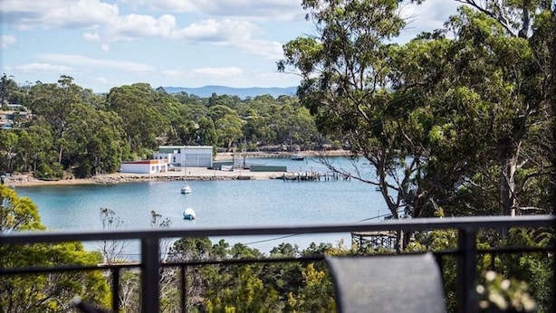 A coastal view with a dock, a small building, and lush greenery. - Cove View Retreat (St Helens)