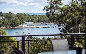 A coastal view with a dock, a small building, and lush greenery. - Cove View Retreat (St Helens)