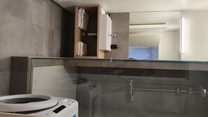 Un bany modern amb dutxa de vidre, vàter i un armari de fusta amb tovalloles.