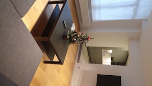 Un saló modern amb terra de fusta, una taula marró fosc i un petit arbre de Nadal.