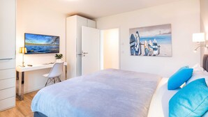 A bedroom with a bed, a desk, and a chair. - Terrace apartment Haffblick - Oasis on the lagoon - Haffblick (6-2) (Garz)